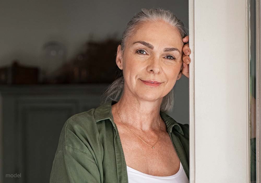 Mature woman in olive green shirt standing in a doorway