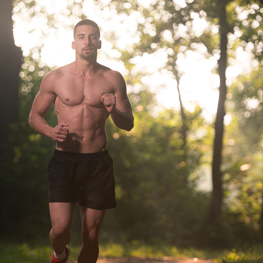 shirtless man runing in a forest